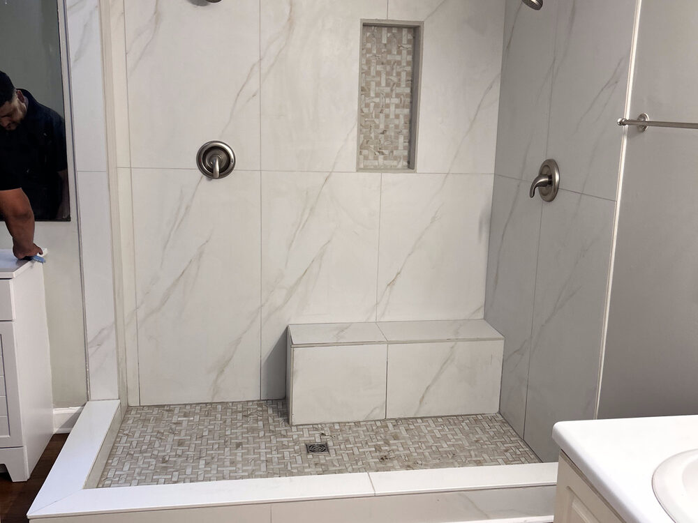 Completed FIG bathroom remodel — marble-look walk-in shower with bench